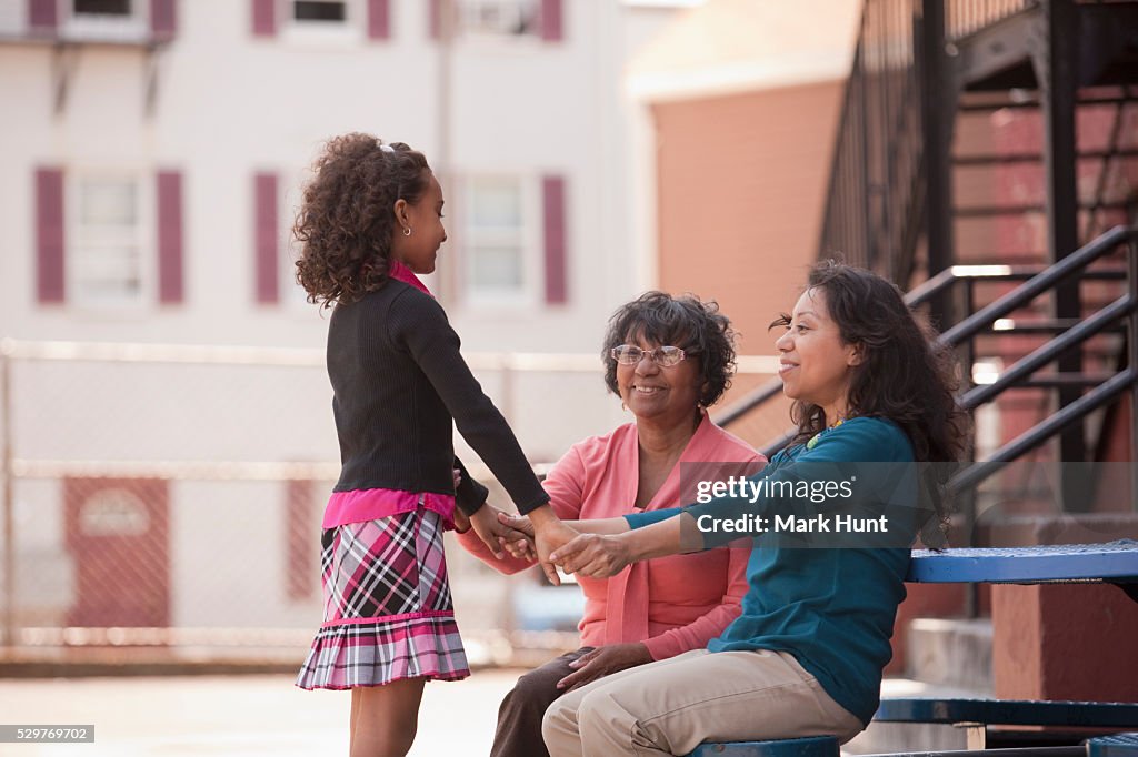 Hispanic girl with her mother and grandmother in the schoolyard