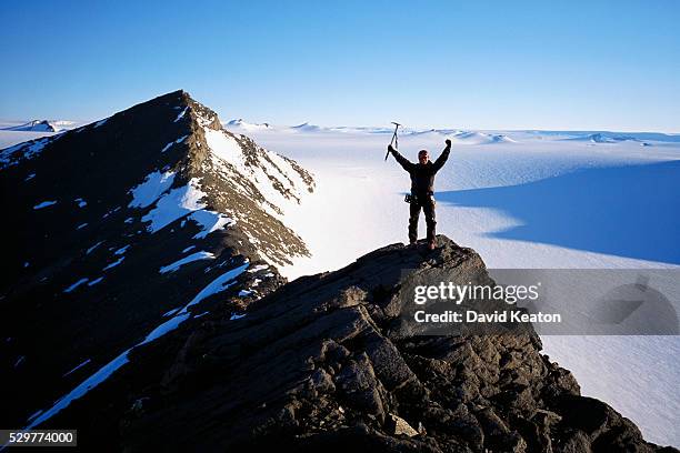 mountaineer standing atop greenland peak - kearton stock pictures, royalty-free photos & images