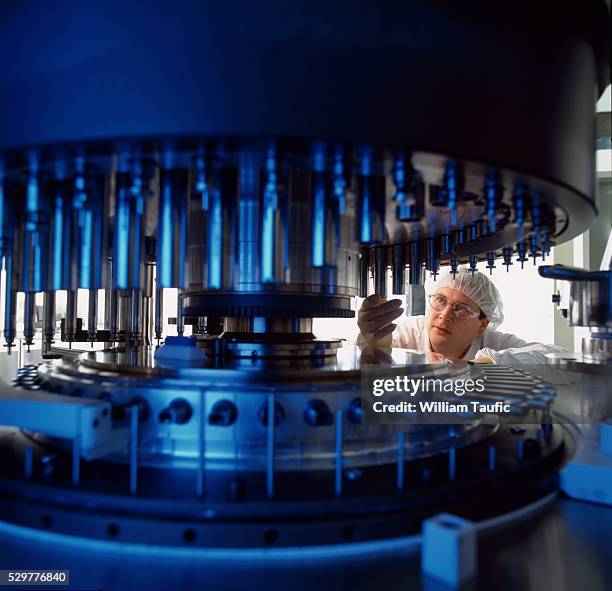 worker at capsule filling machine in pharmaceutical plant - farmaceutische-fabriek stockfoto's en -beelden