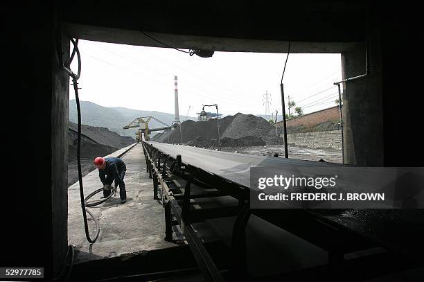 Miner gathers a rubber coil beside a shaft that transports coal for processing at a mine in Huangling county, north of Xian, 25 May 2005, in western...