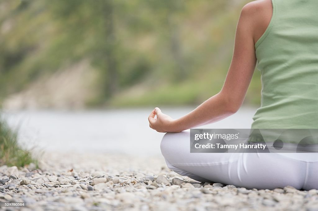 Woman meditating at edge of river