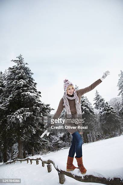 young woman in cap and jacket walking on log - women winter snow stock-fotos und bilder
