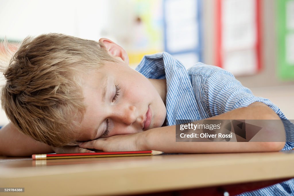 Boy sleeping on desk in classroom