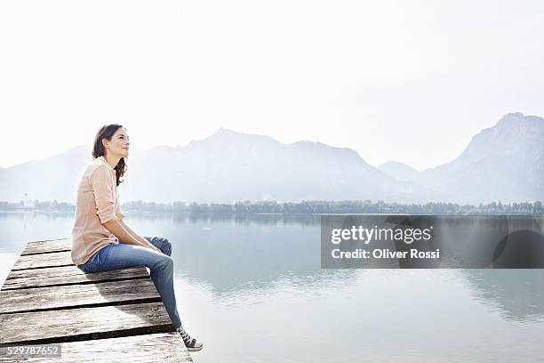 woman sitting on dock - woman pier stock pictures, royalty-free photos & images