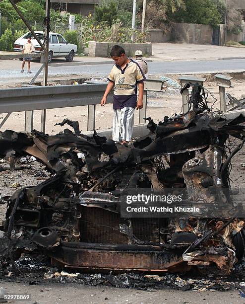 An Iraqi boy looks at a damaged car at the scene of a suicide car bomb explosion which failed to hit a U.S. Military convoy May 25, 2005 in the area...