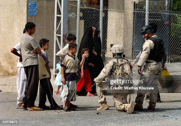 People watch as a U.S. Soldier and an Iraqi translator secure the scene of a suicide car bomb explosion which failed to hit a U.S. Military convoy...