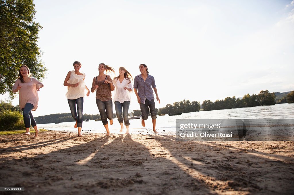 Young friends running beside a lake