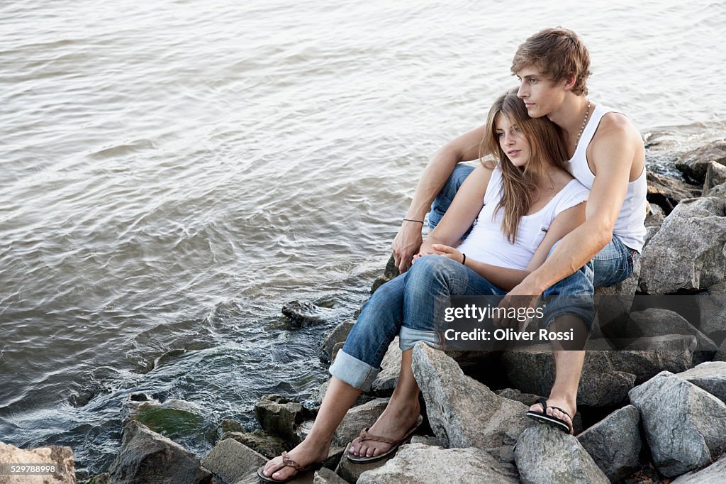 Young couple sitting on rocks by the water