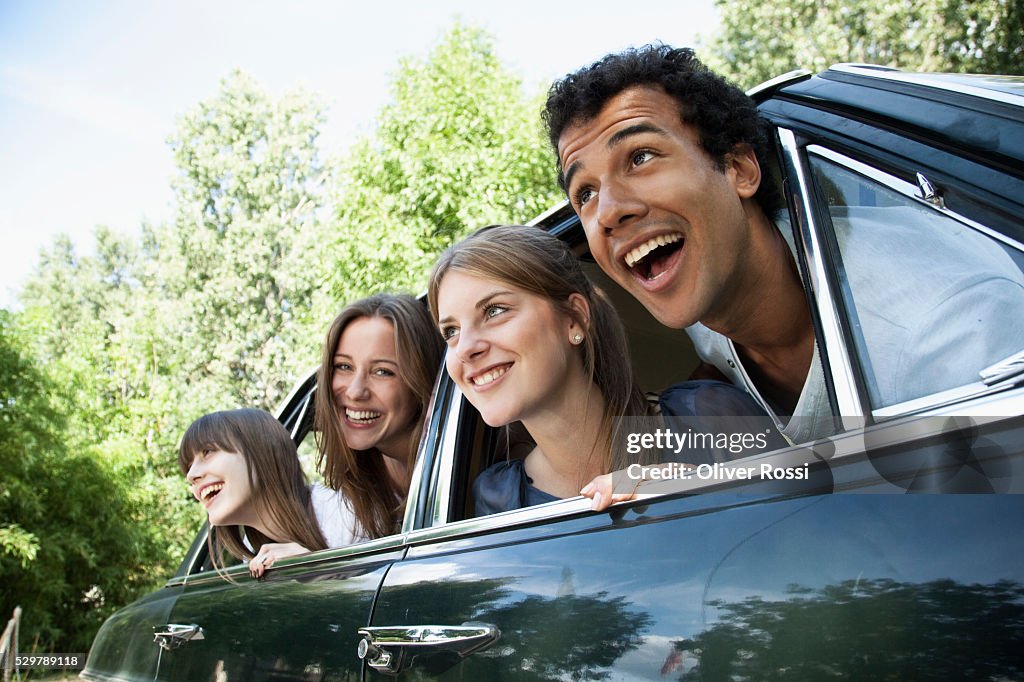 Young friends leaning out car windows
