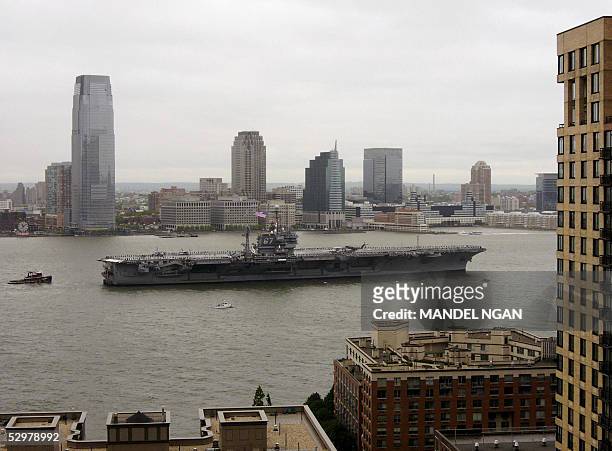 The aircraft carrier USS John F. Kennedy makes its way up the Hudson River 25 May past apartment buildings in Battery Park in lower Manhattan. The...