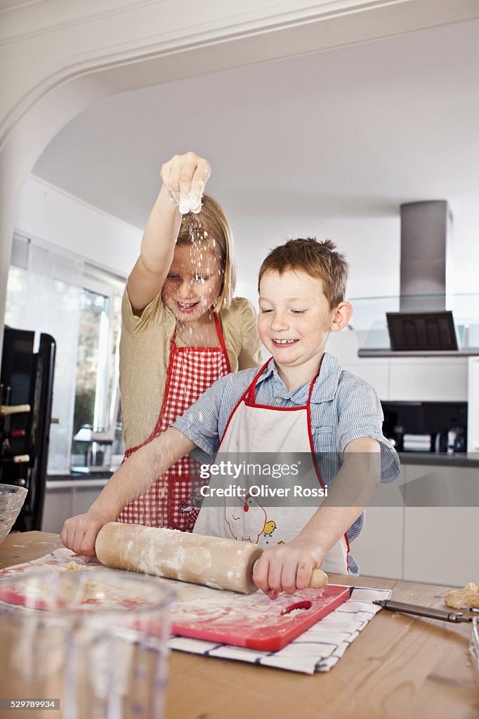 Kids ( 5-6) wearing aprons and preparing dough in kitchen