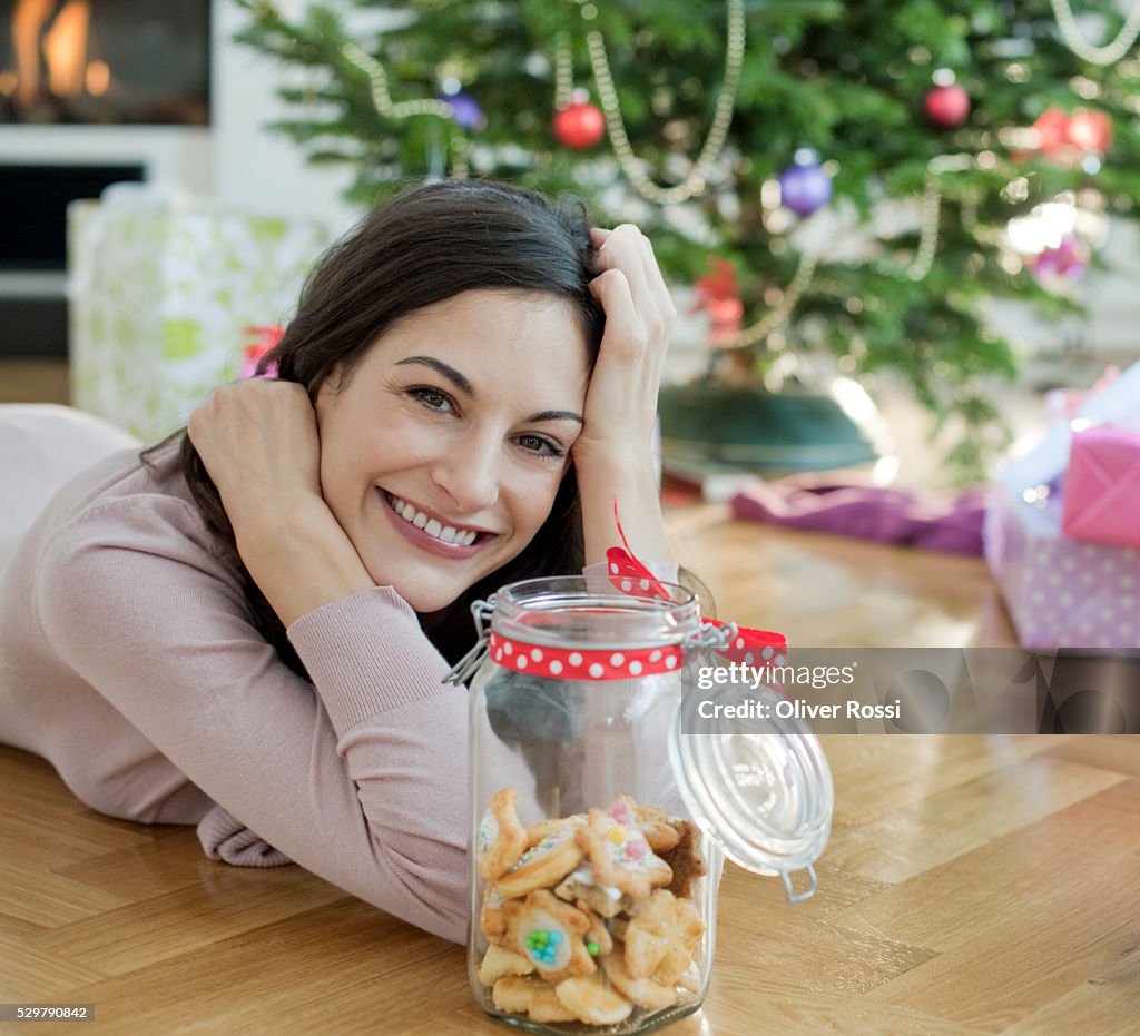 Portrait of woman with cookie jar by Christmas tree