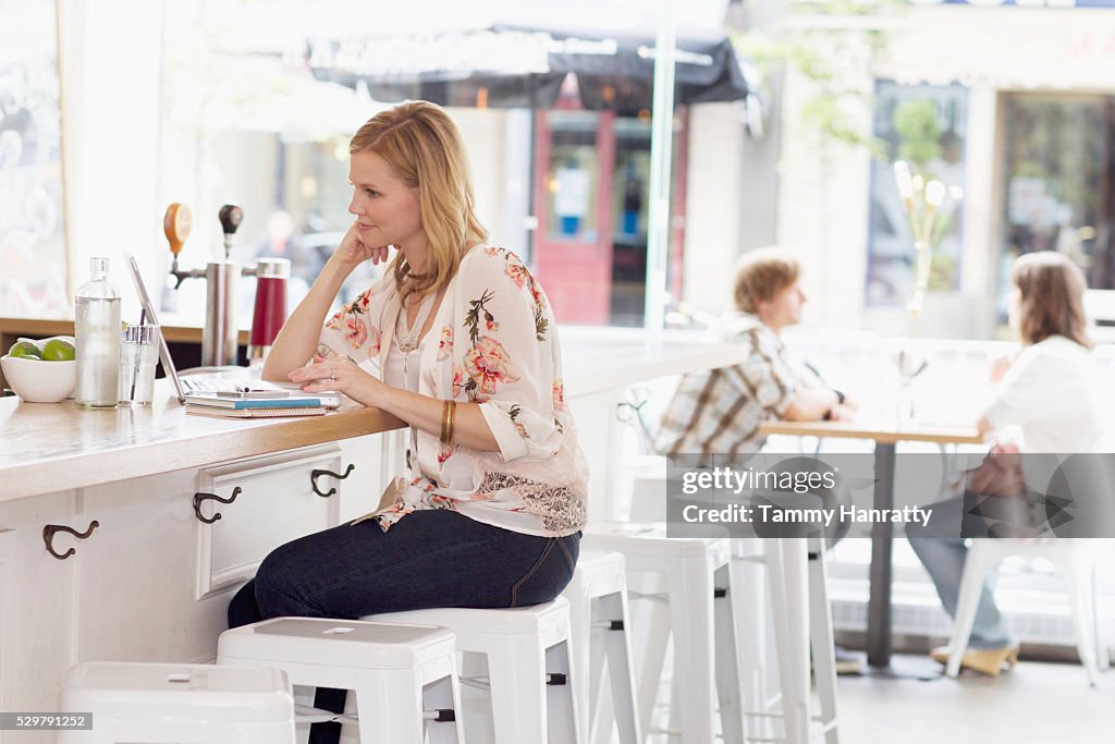 Woman sitting and bar counter and using laptop