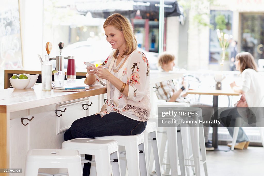 Young woman texting at bar counter