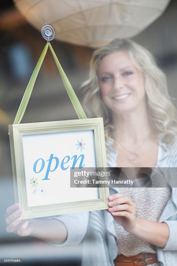 Sales clerk putting up open sign