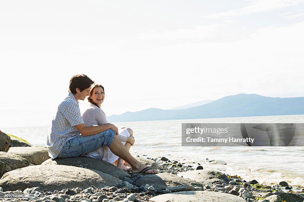 Young couple at sea relaxing on rock