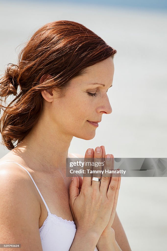 Mid-adult woman meditating while practicing yoga