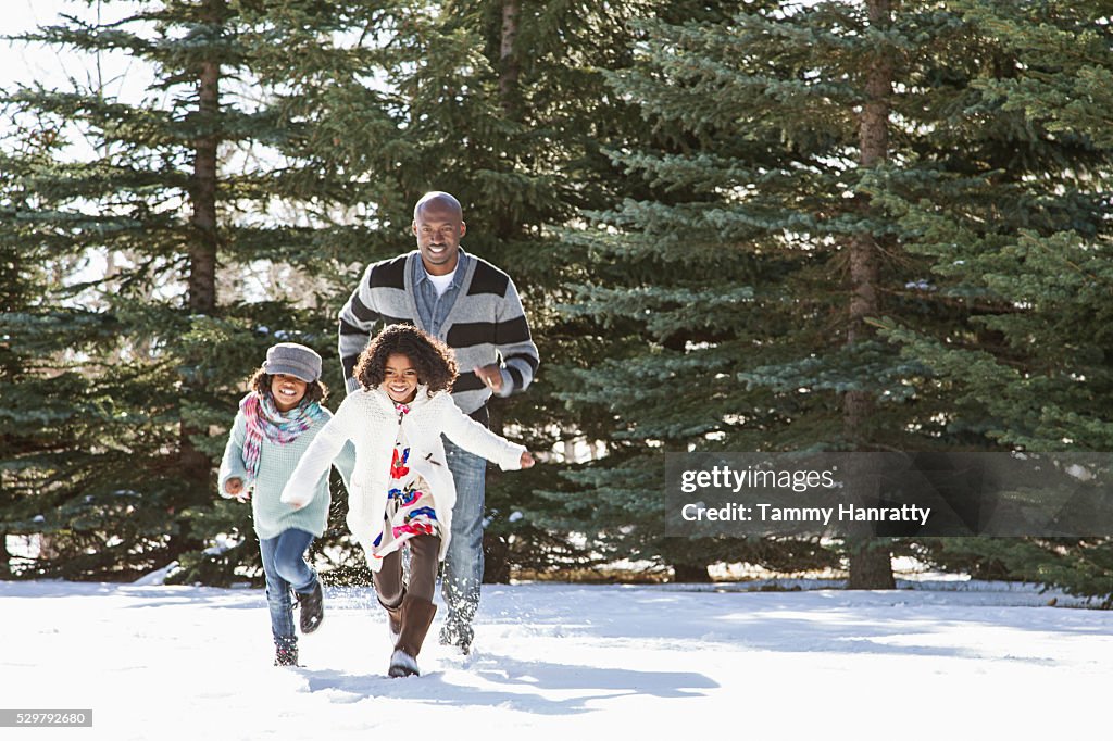 Sisters (8-9,10-12) playing on snow with their father