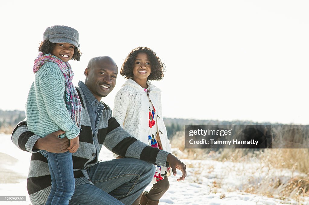 Sisters (8-9,10-12) posing with her father on snow