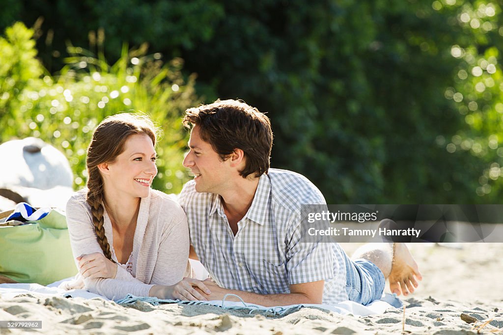 Young couple relaxing on sand outdoors
