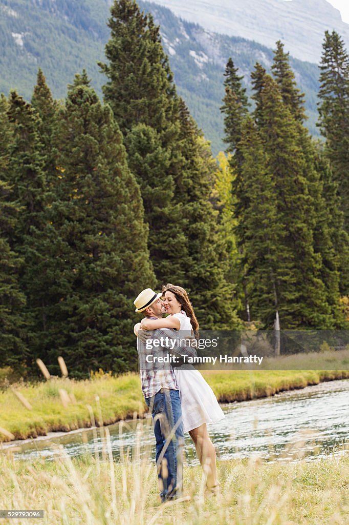 Mid-adult couple embracing and kissing at lakeshore