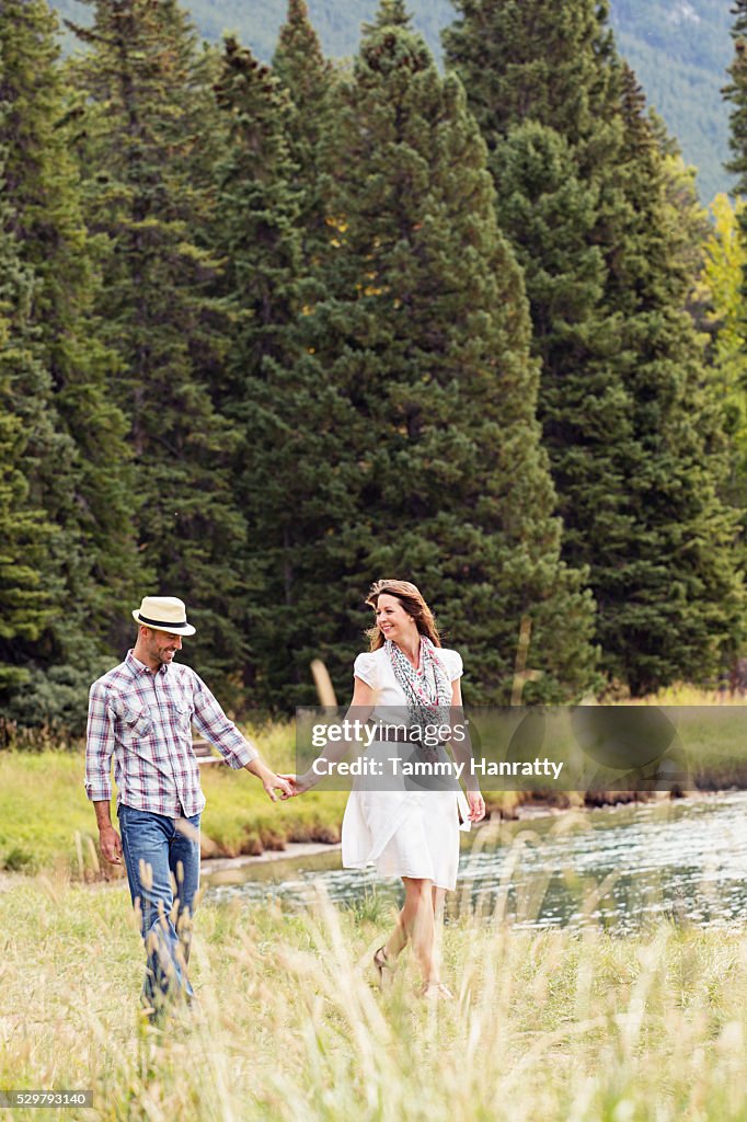 Mid-adult couple holding hands and relaxing while walking at lakeshore