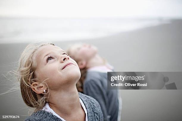 two girls (5-6, 7-9)on beach looking up - looking up stock pictures, royalty-free photos & images