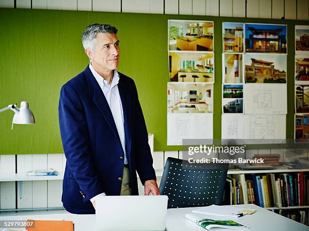 businessman standing at workstation in office - veste homme photos et images de collection