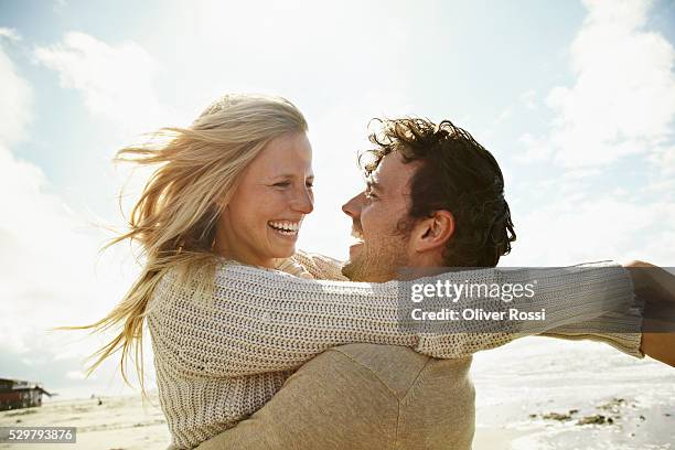 happy couple embracing on beach - gezicht aan gezicht stockfoto's en -beelden