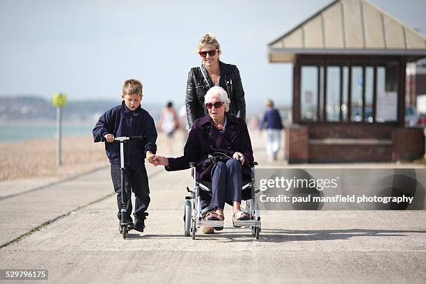 senior lady being pushed in wheelcahir - beach shelter stockfoto's en -beelden