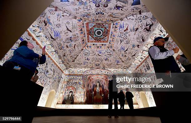 People visit the "Cave Temples of Dunhuang: Buddhist Art on the Silk Road" exhibit at the Getty Center in Los Angeles on May 9 viewing a full-scale,...