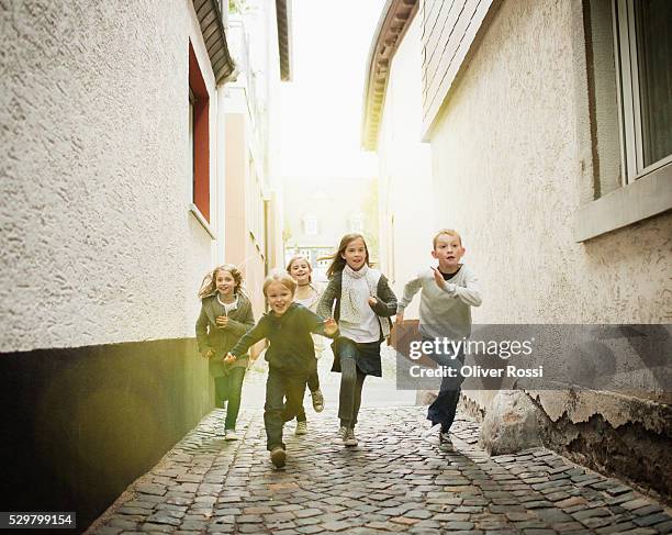 kids (10-12, 6-7) running on street - 子供のみ ストックフォトと画像