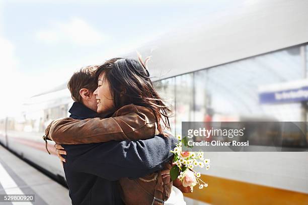 mix-race couple embracing on railway station platform - station stock-fotos und bilder