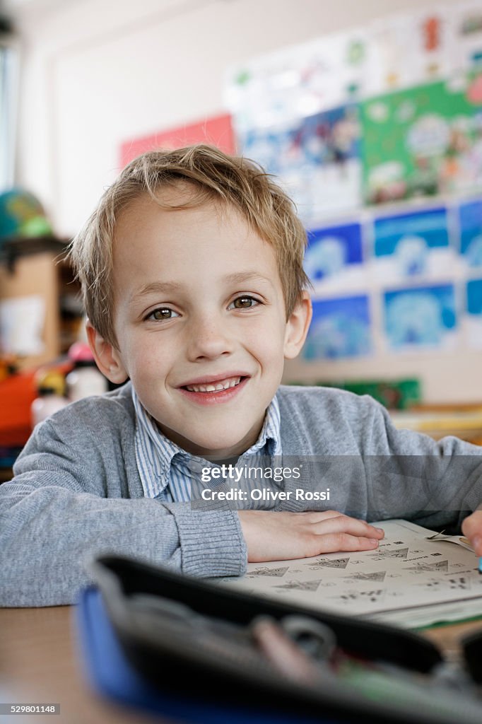 Happy school boy (8-9) sitting in class room