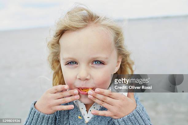 blond girl eating chips on the beach - tentempié salado fotografías e imágenes de stock