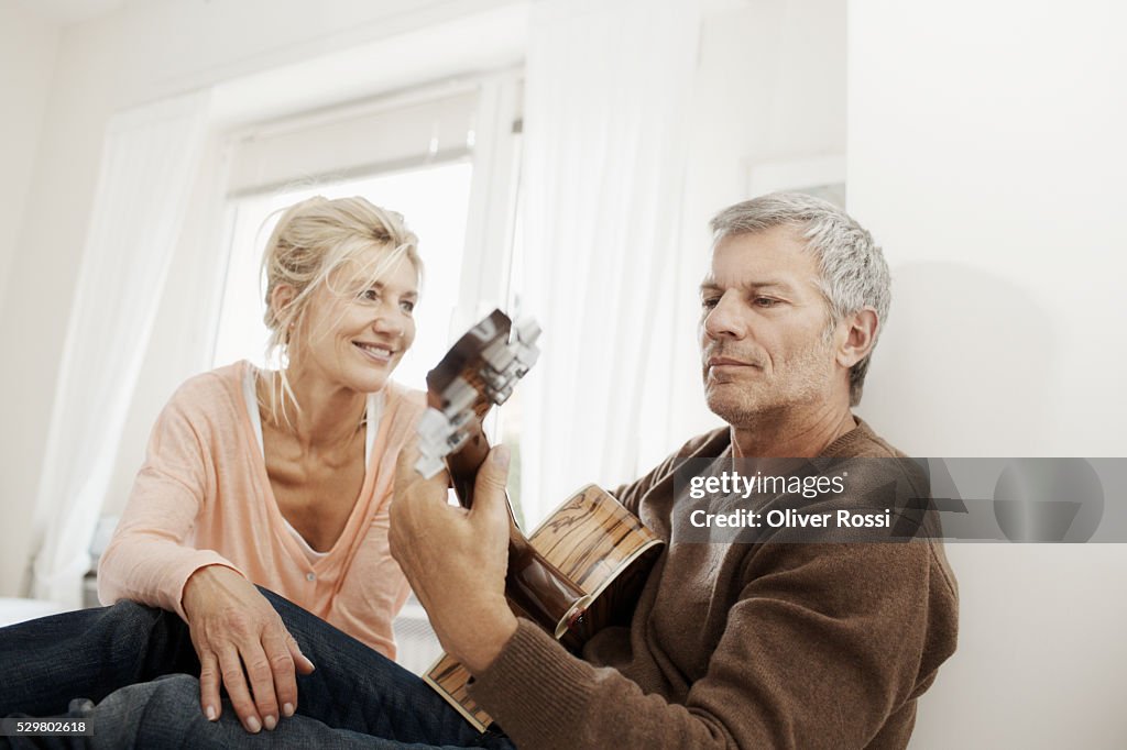 Mature woman looking at man playing guitar