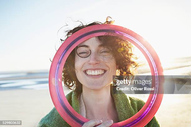 happy woman with flying disc on the beach - frisbee stock-fotos und bilder