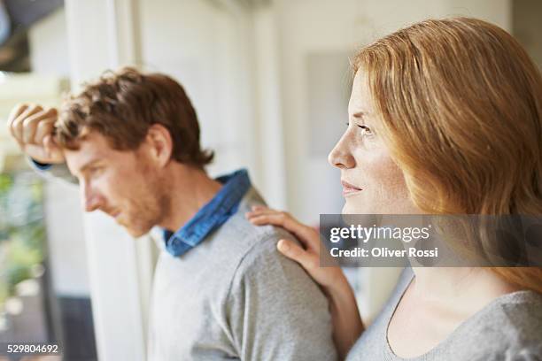 pensive couple looking out window - couple unhappy stock pictures, royalty-free photos & images
