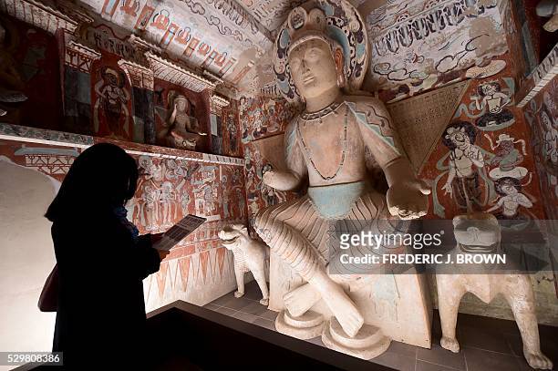 People visit the "Cave Temples of Dunhuang: Buddhist Art on the Silk Road" exhibit at the Getty Center in Los Angeles on May 9 viewing a full-scale,...