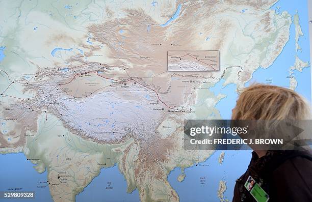 Woman walks past a map of China and Central Asia with red line signifying the ancient trade route known as thr Silk Road at the "Cave Temples of...