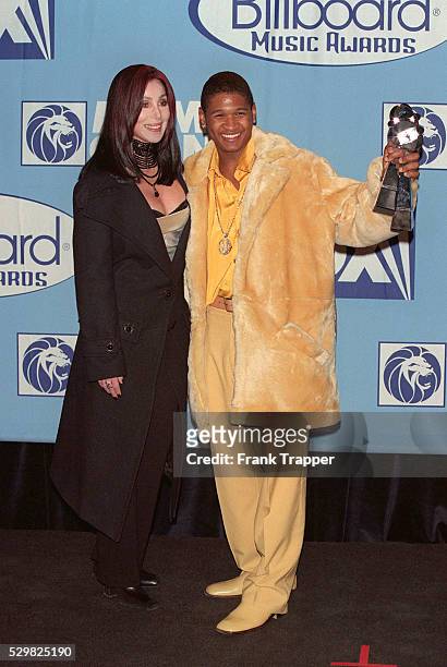 Cher, who hosted the ceremony, and Usher with his artist of the year awards.