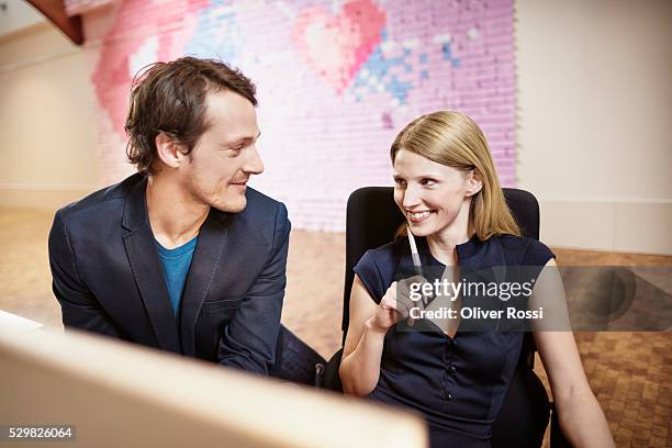 smiling businessman and businesswoman in office - office romance stock pictures, royalty-free photos & images