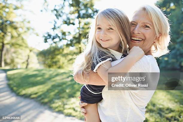 grandmother carrying granddaughter outdoors - granddaughter stockfoto's en -beelden