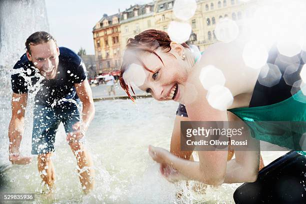 friends splashing in water of fountain - fountain fotografías e imágenes de stock