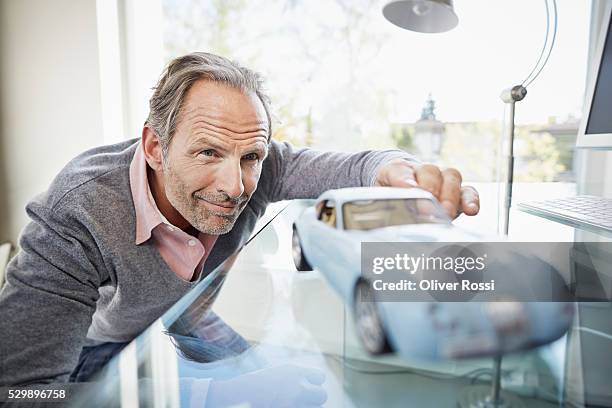 confident mature man looking at model car - car collection photos et images de collection