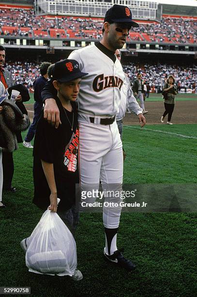 Will Clark of the San Francisco Giants and his son gather on the field after a 7.1 magnitude earthquake struck the Bay Area, postponing Game three of...