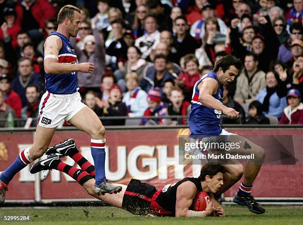 Matthew Lloyd for the Bombers lands after taking a mark between Chris Grant and Brian Harris for the Bulldogs during the AFL Round 10 match between...