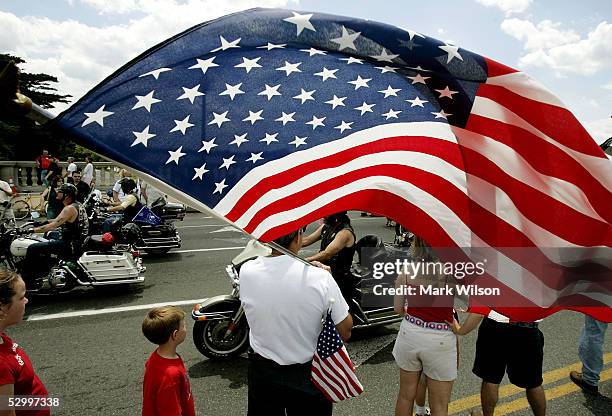 Spectater holds an American flag while motorcycle riders participating in Rolling Thunder ride across Memorial Bridge May 29, 2005 in Washington, DC....