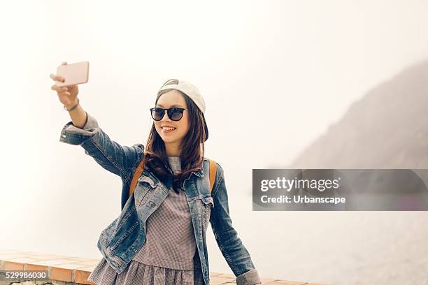 Asian traveler taking selfie with ocean view, soft warm tone