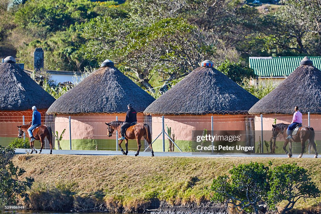 Tourist horse ridding past Xhosa mud huts